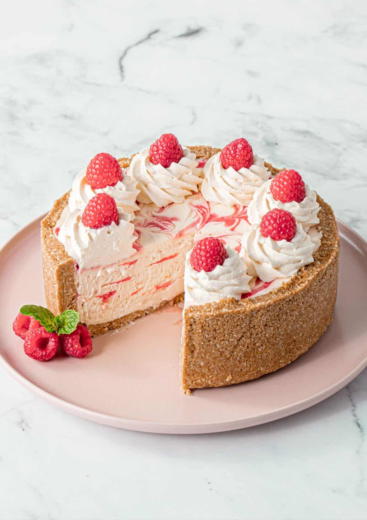 a no-bake cheesecake with slice taken out and raspberry swirled through it.