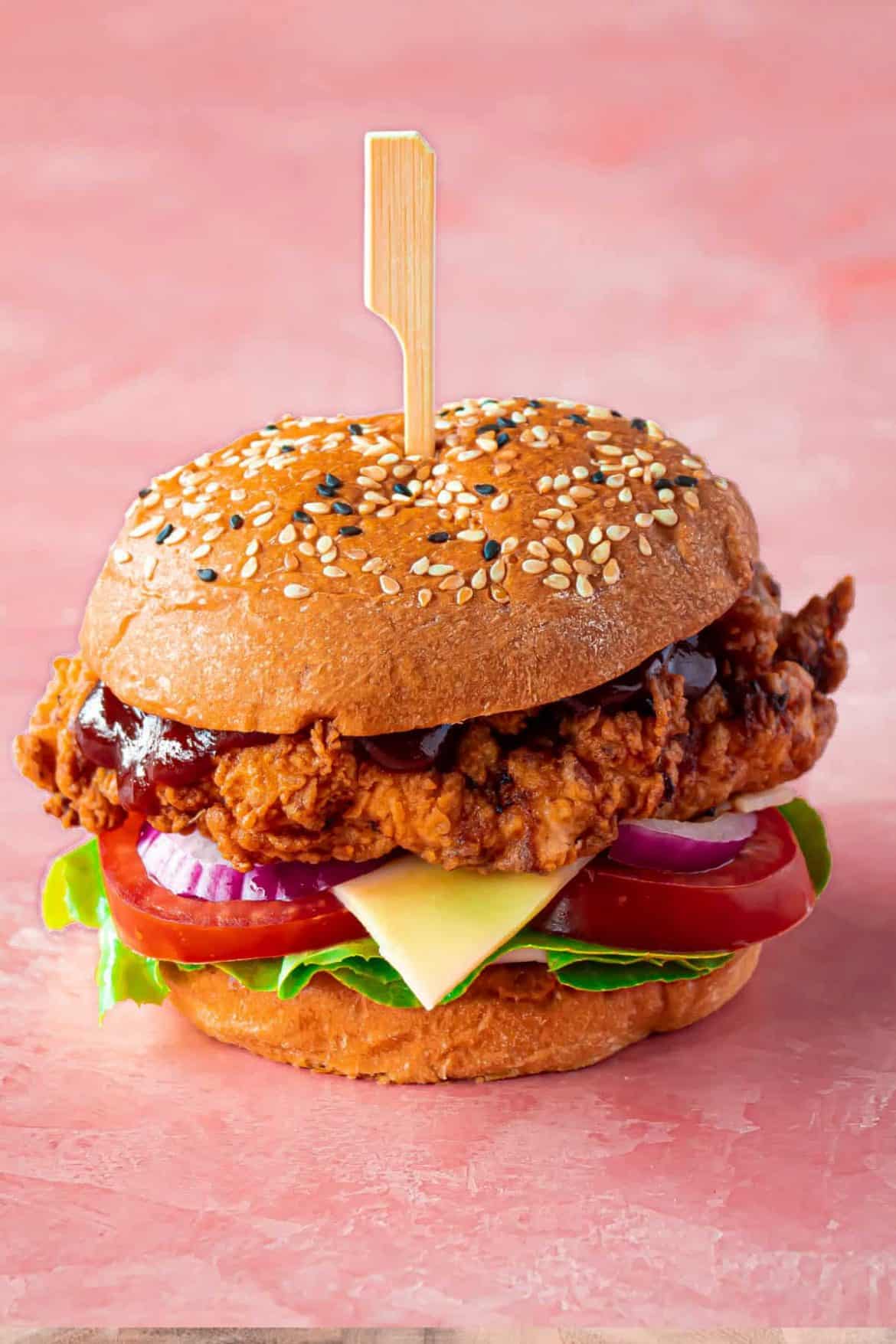 Chicken burger that is crispy sitting on a pink background