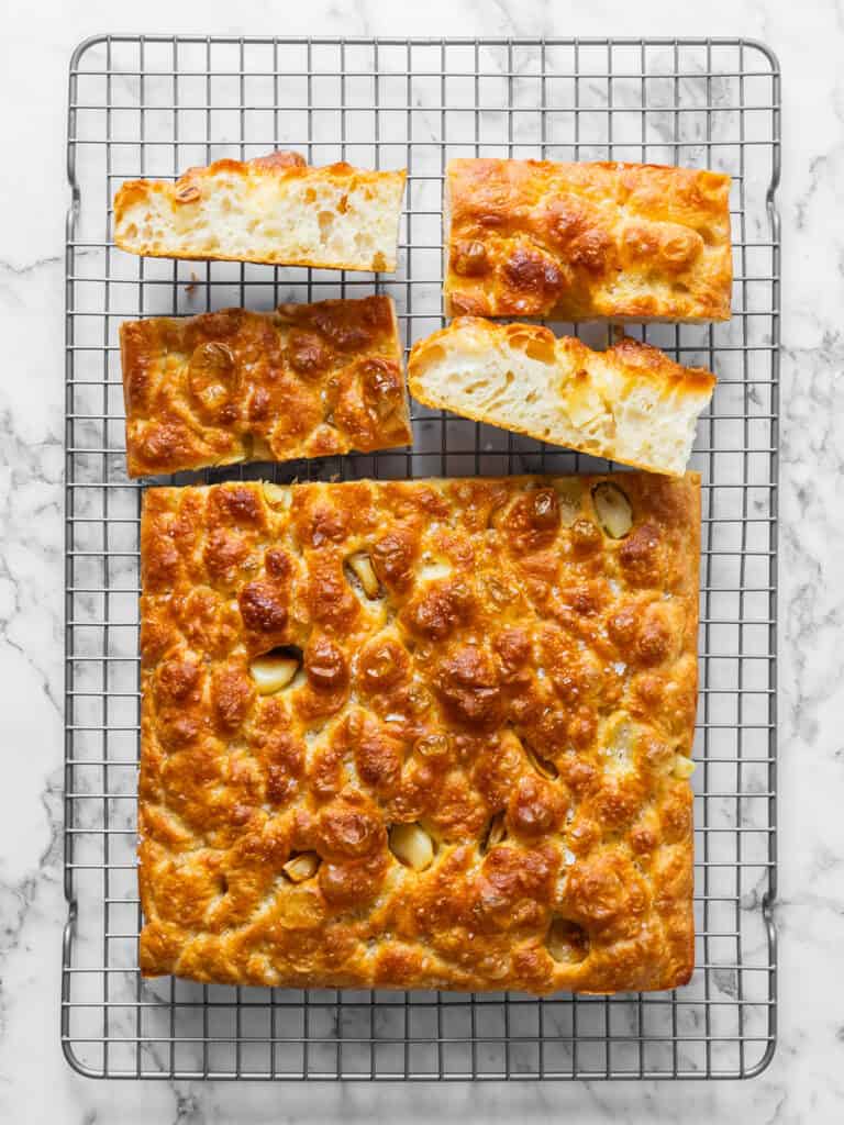 Top down shot of sliced up light and airy chewy Italian garlic flatbread on a cooling rack