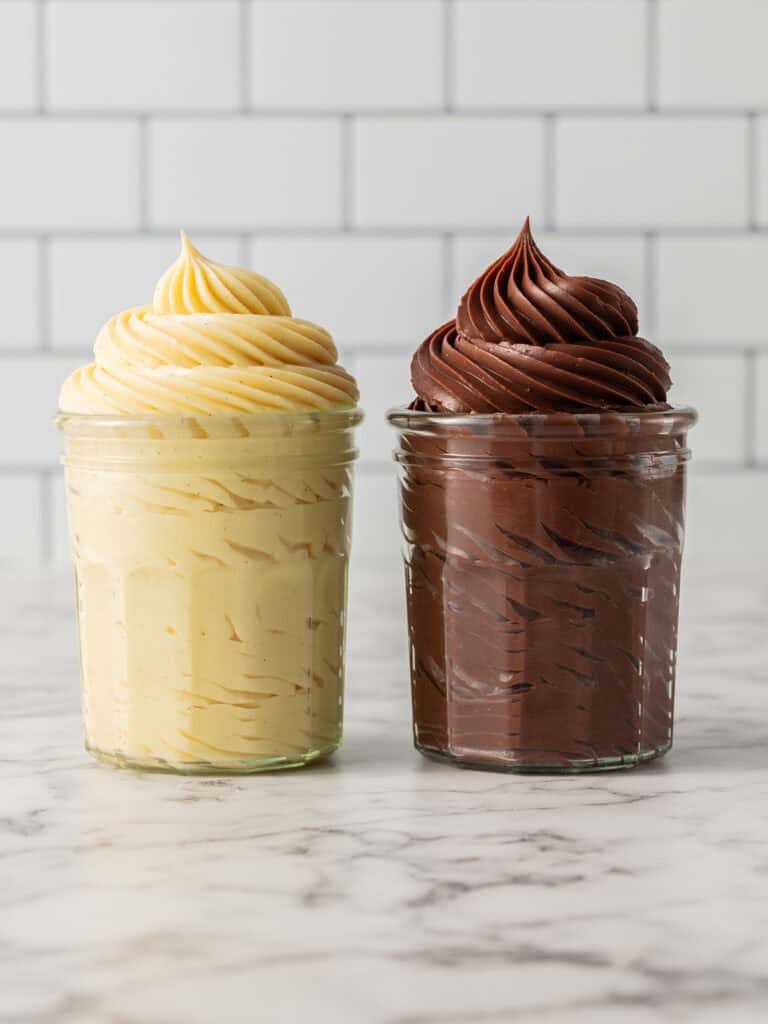 Vanilla custard pudding and chocolate custard swirled and piped in seperate glasses sitting on a benchtop