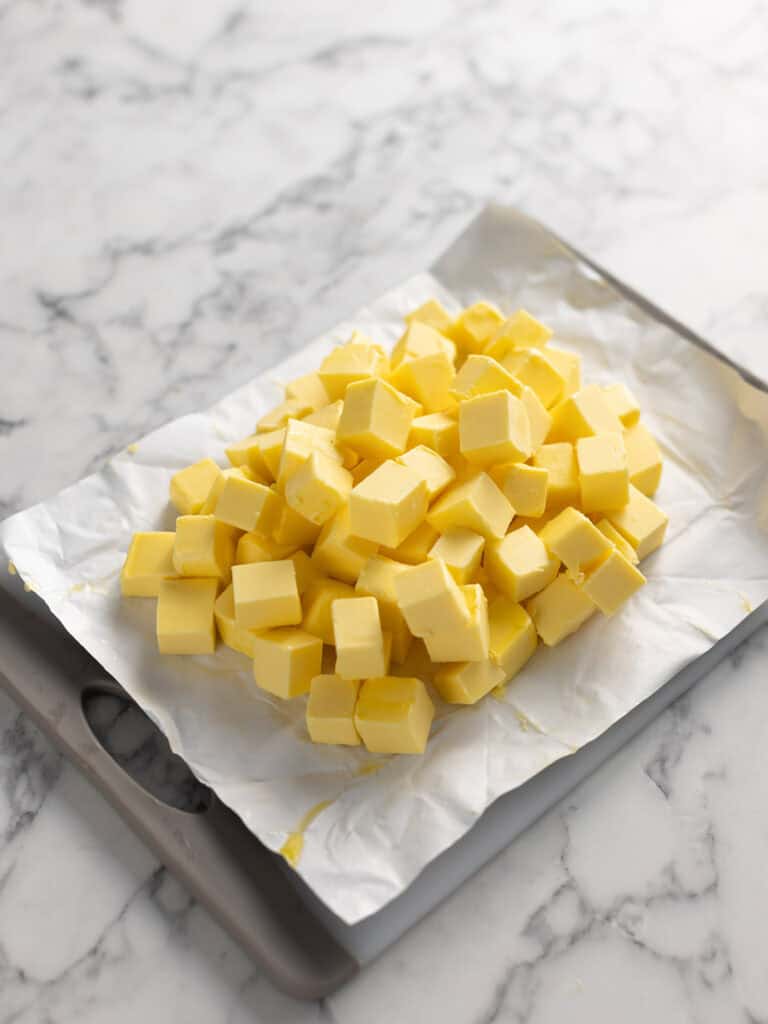 Cubed up butter sitting on a butter package and chopping board waiting to be softened.