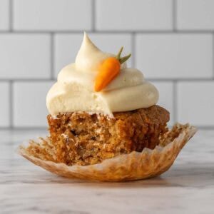 Square image of a single cupcake with frosting on top and a bit taken out