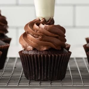 Square image of a cupcake being piped with frosting