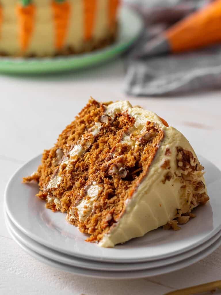 A slice of cake sitting on a plate with the cake in the background