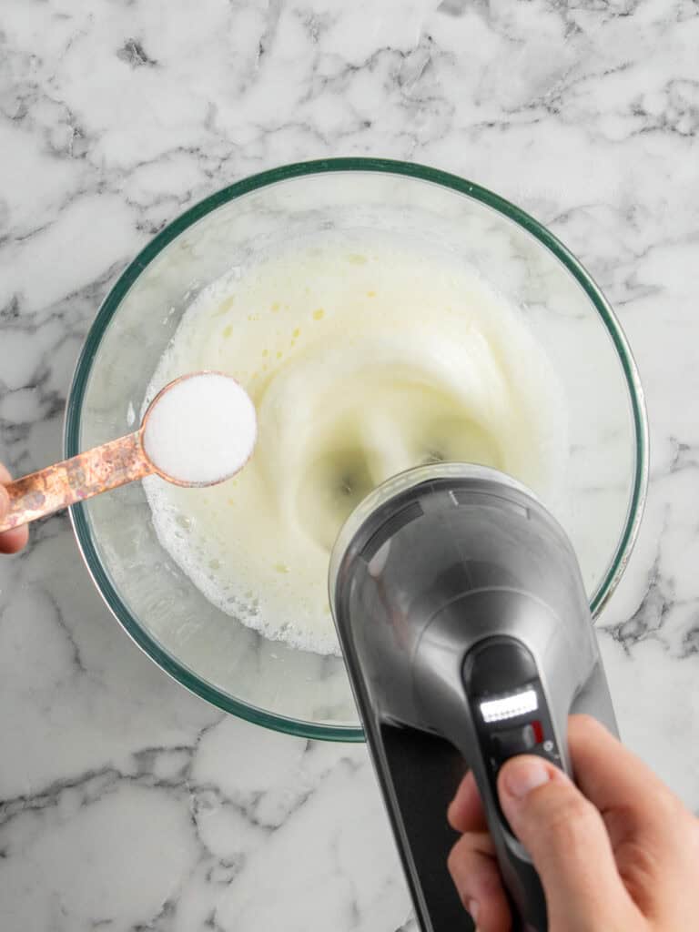 Adding sugar into the egg whites to make the meringue