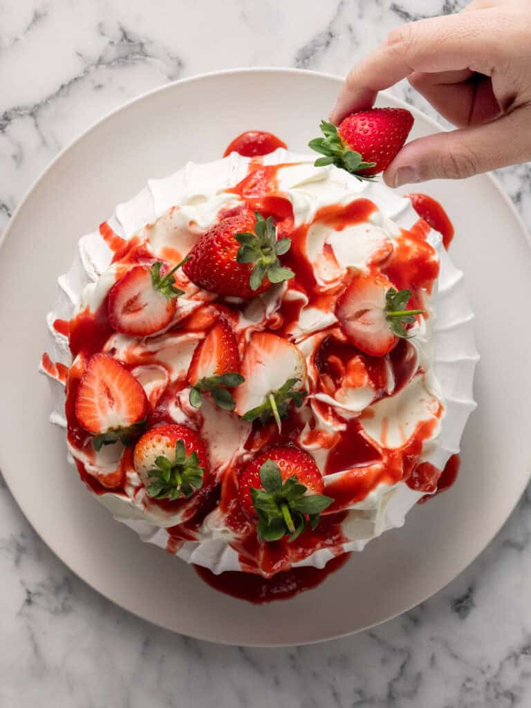 Adding the strawberry sauce and strawberries on top of the baked meringue