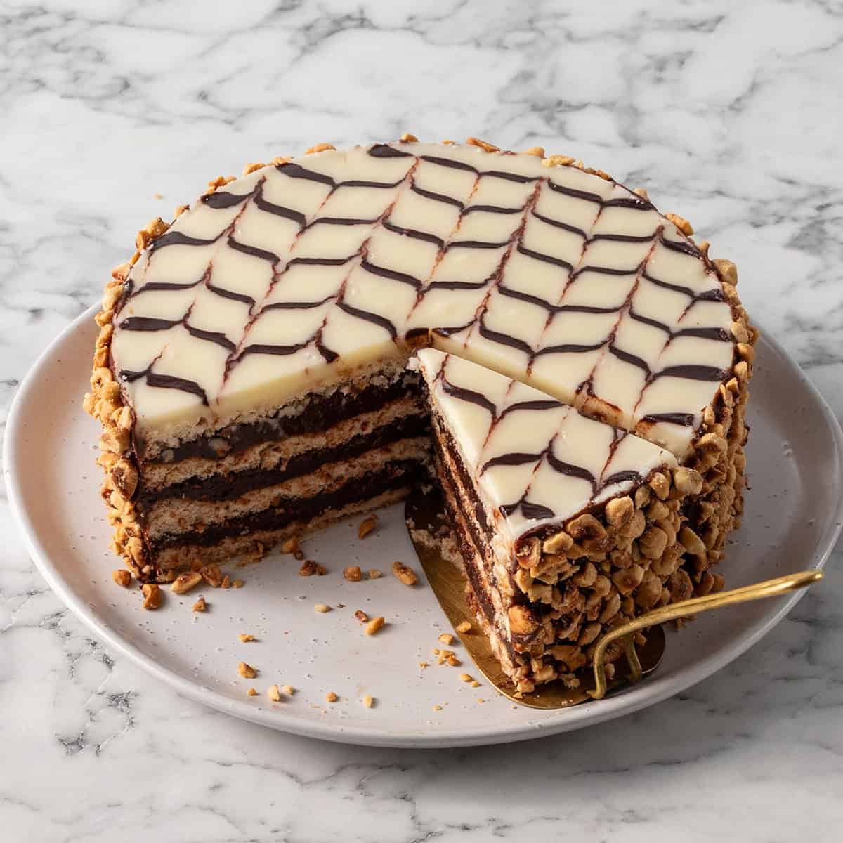 A square image of a chocolate and hazelnut cake with a slice taken out