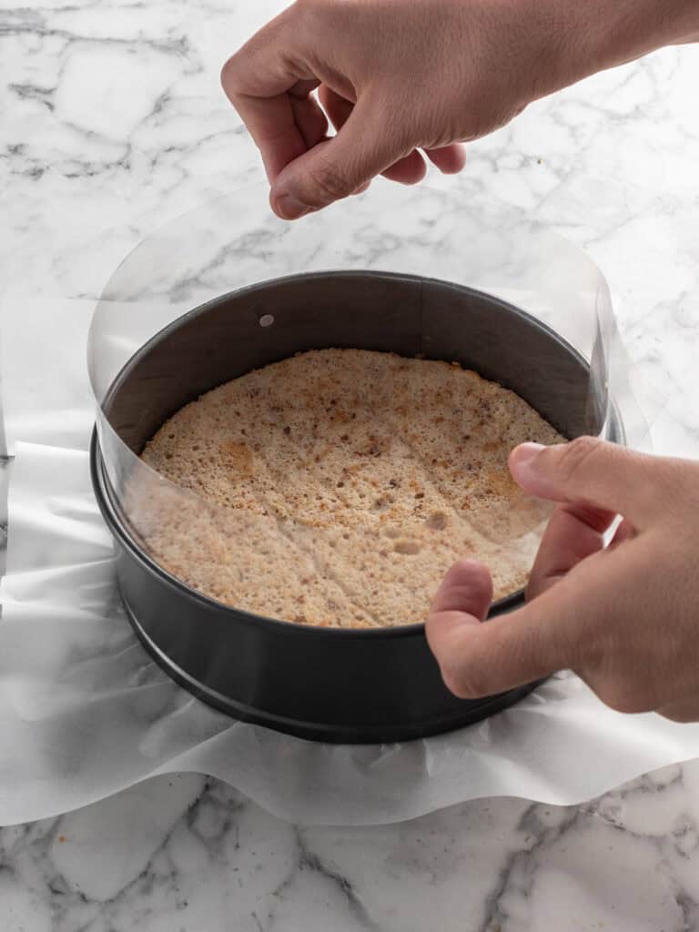Adding the acetate into the springform pan after the first cake layer has been added