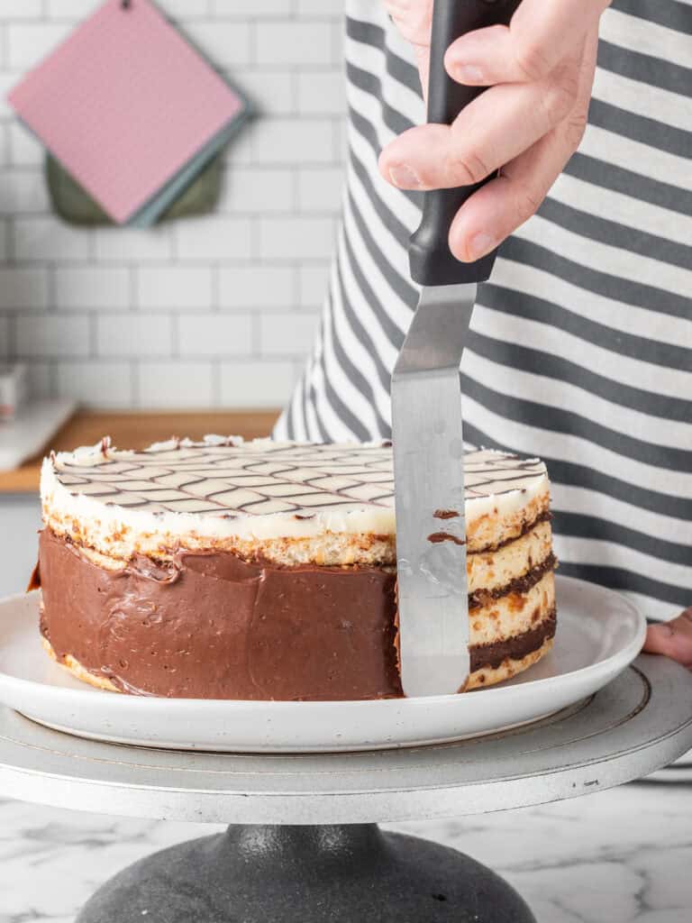 Spreading the remaining pastry cream around the sides of the cake using a spatula