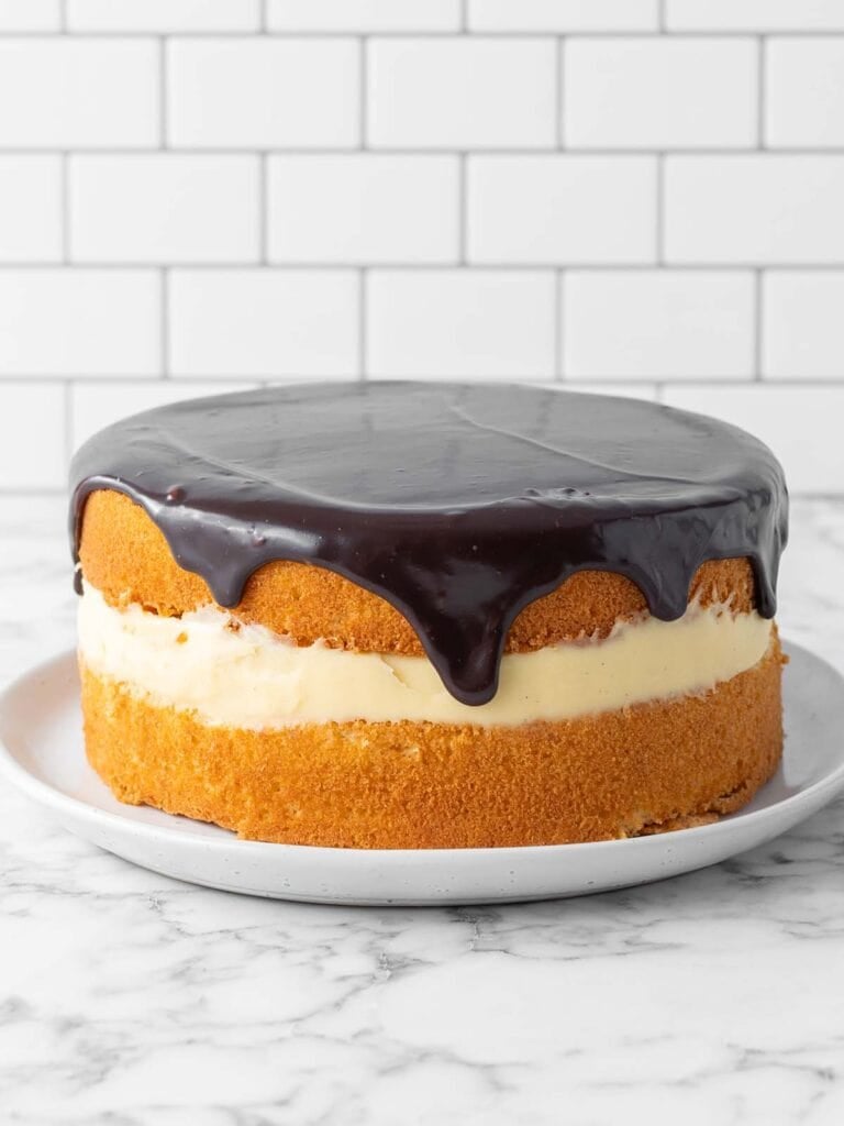 A sponge cake with custard covered in chocolate sauce