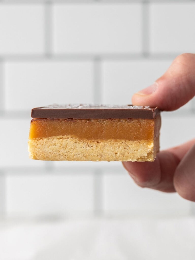 Hand holding a single caramel and shortbread bar