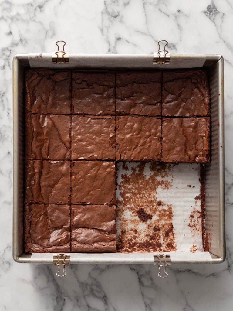 Top down shot of chocolate brownies in the tin all sliced up with some missing