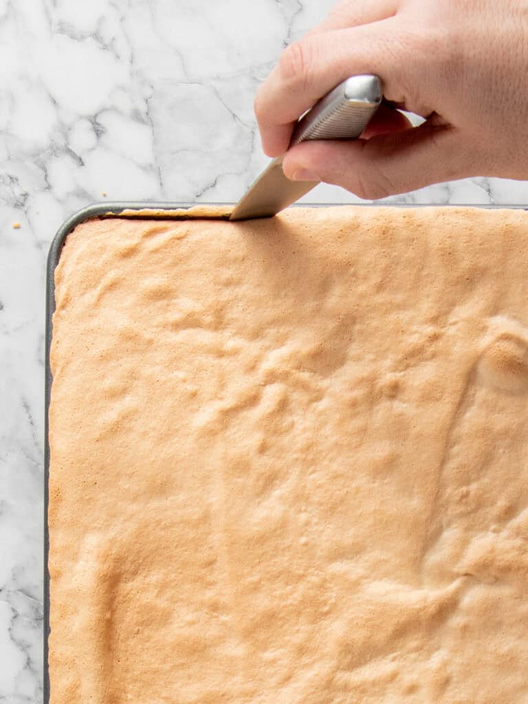 Using a knife to release the cake from the sides of the tray