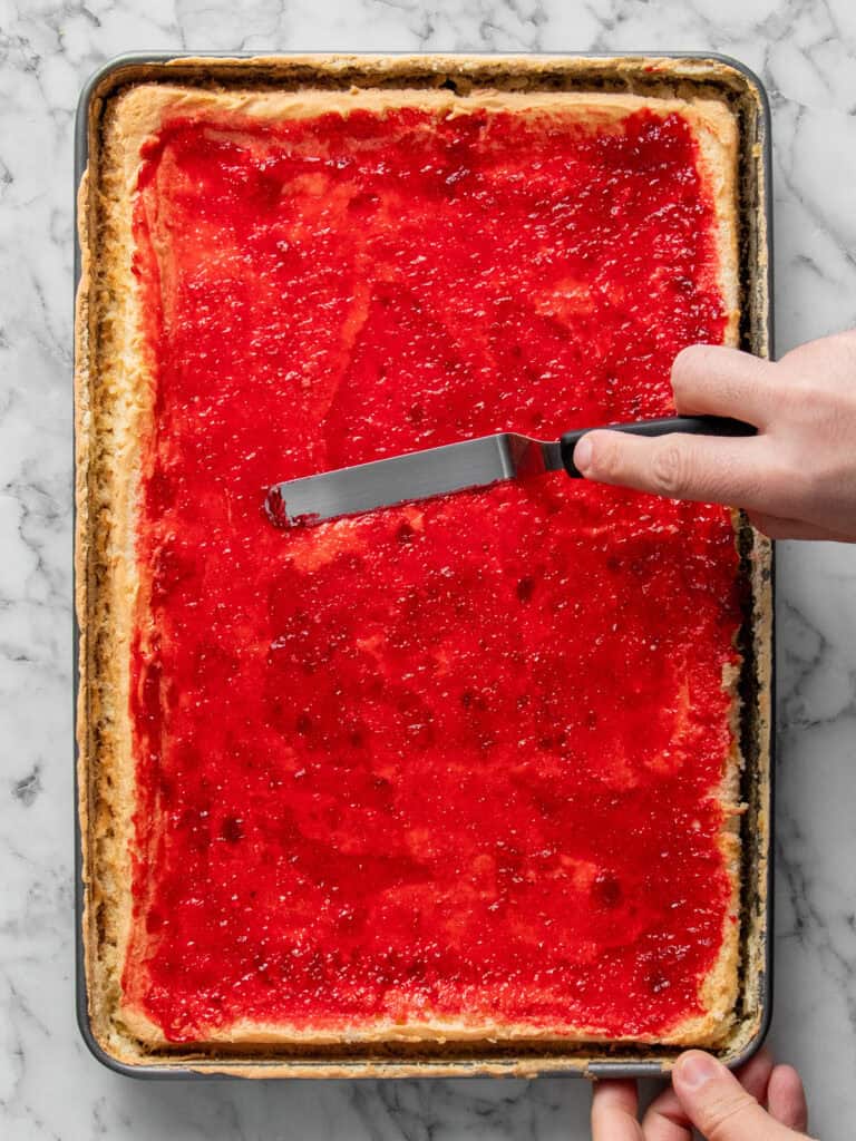 Spreading the raspberry jam on top of the sponge