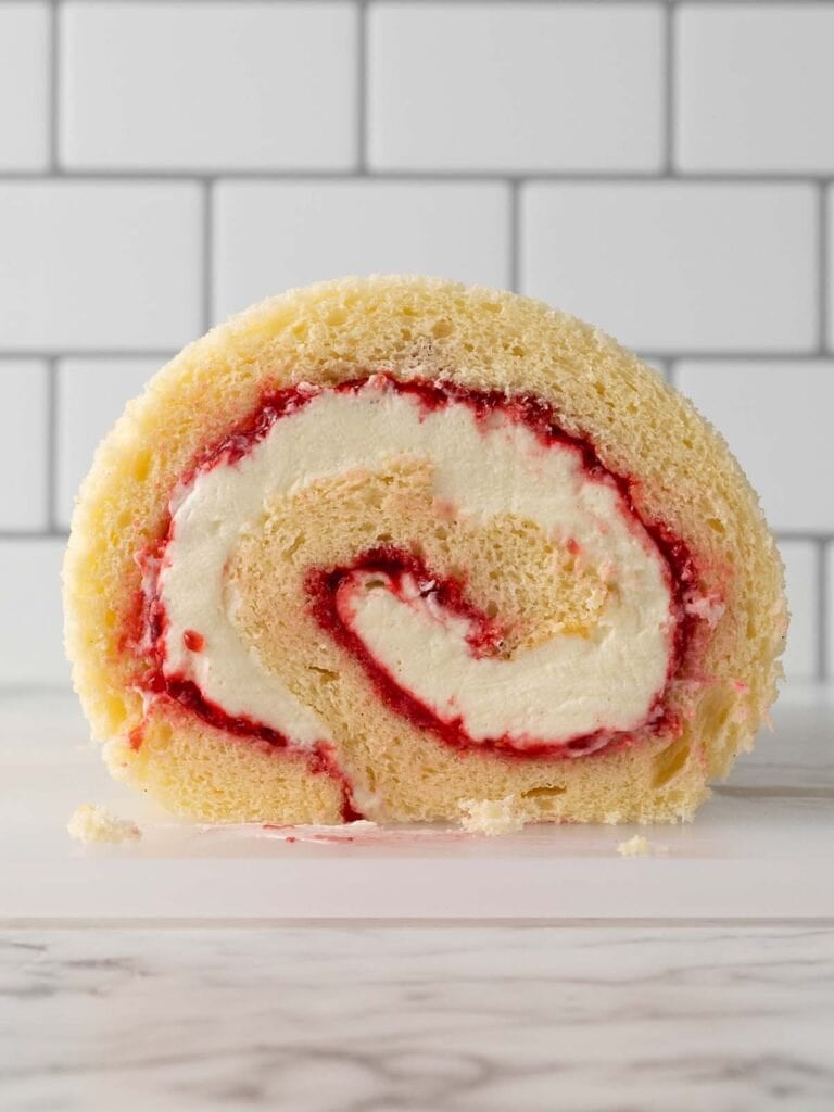 A front on shot of a spiral log cake filled with chantilly cream and raspberry jam