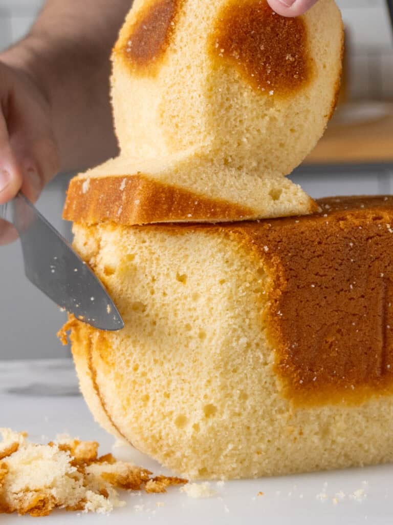 Trimming away any excess cake from the front of the square cake to be flush with the loaf cake piece.