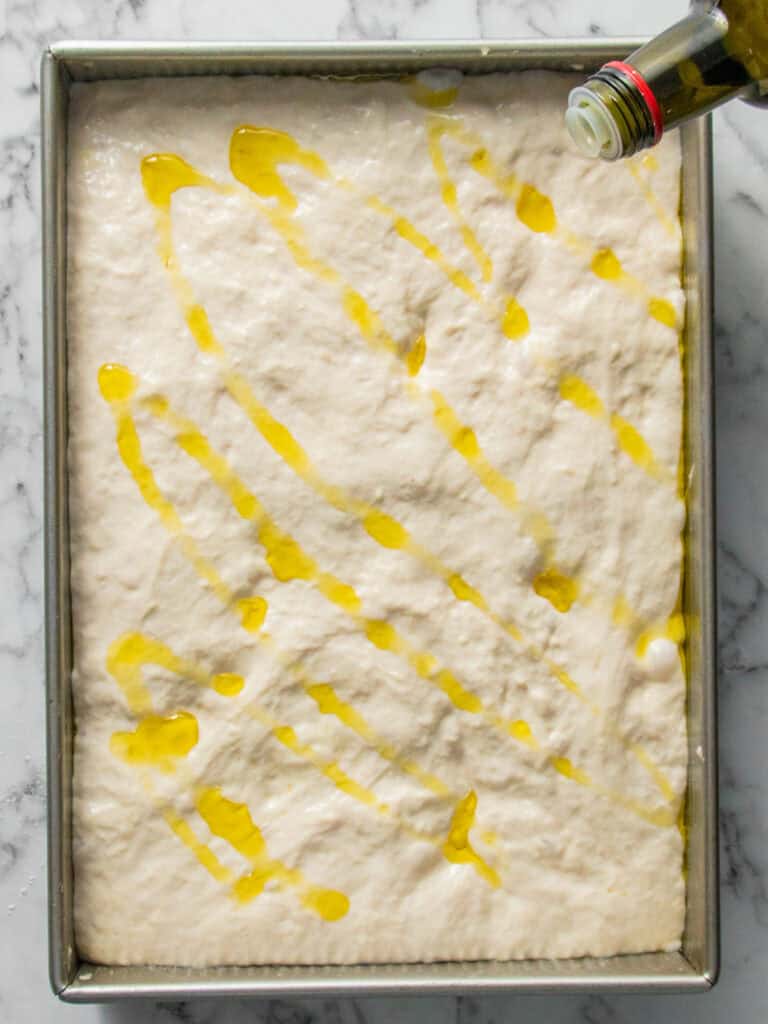 Adding olive oil on top of the risen dough