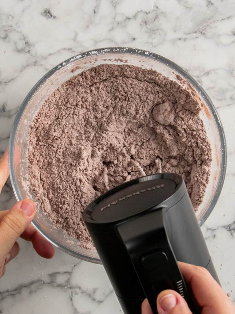 Using an electric mixer to mix in the butter until it looks crumbly