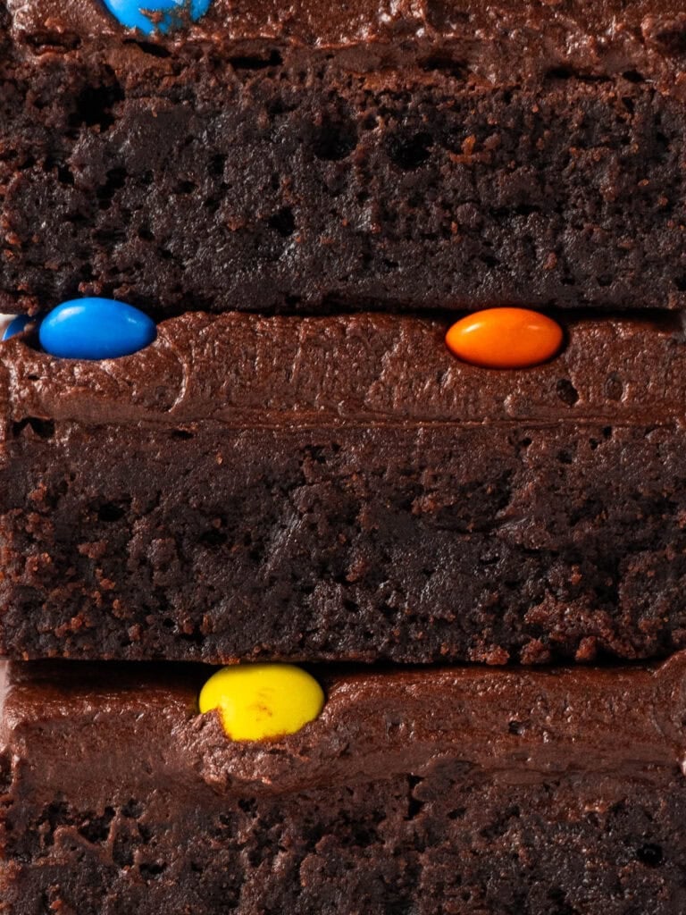Extreme close up of a stack of frosted brownies with m&m's on top