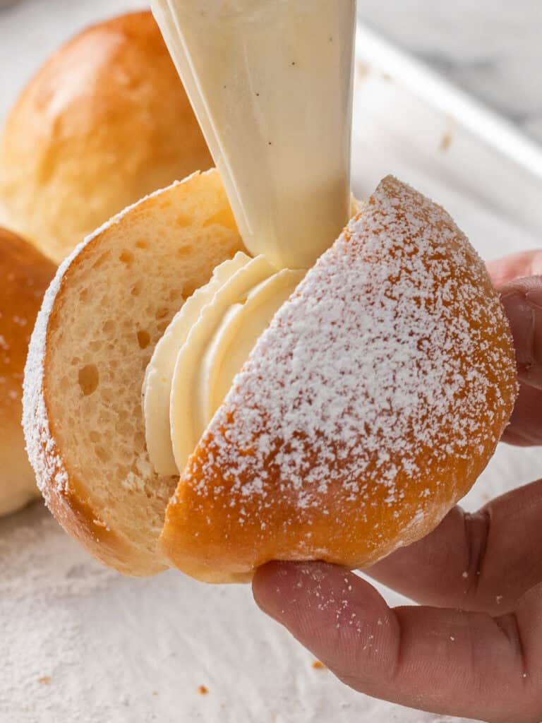 Piping some cream on top of the jam to seal it up