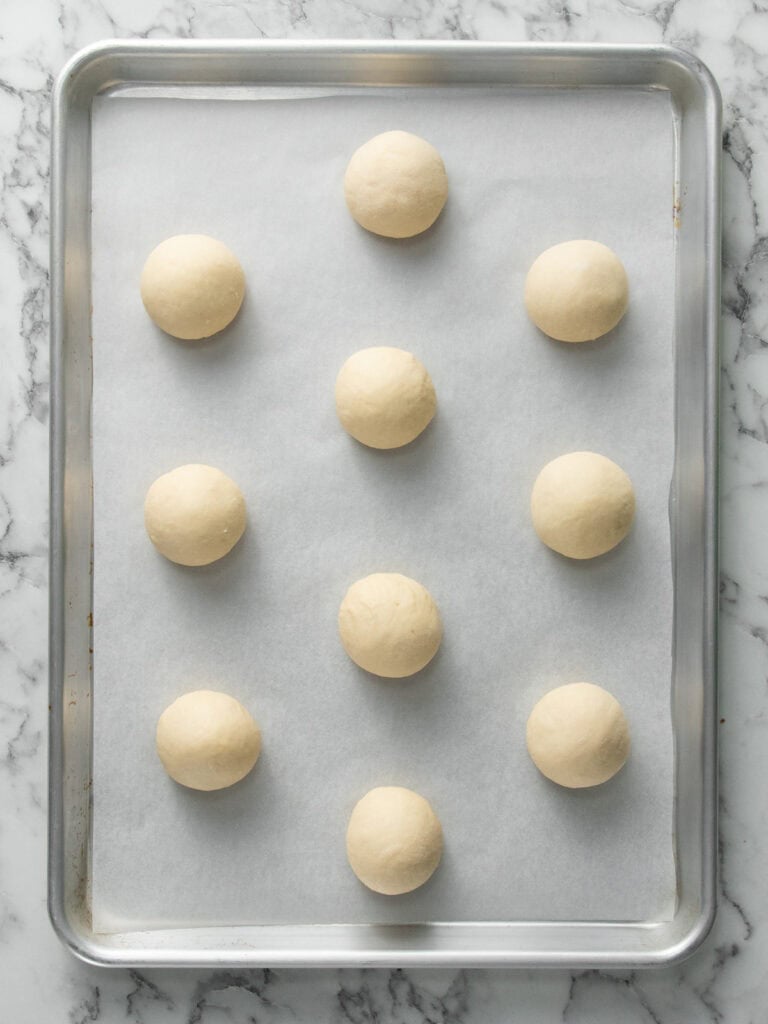 Placing the buns on a baking tray so they can rise