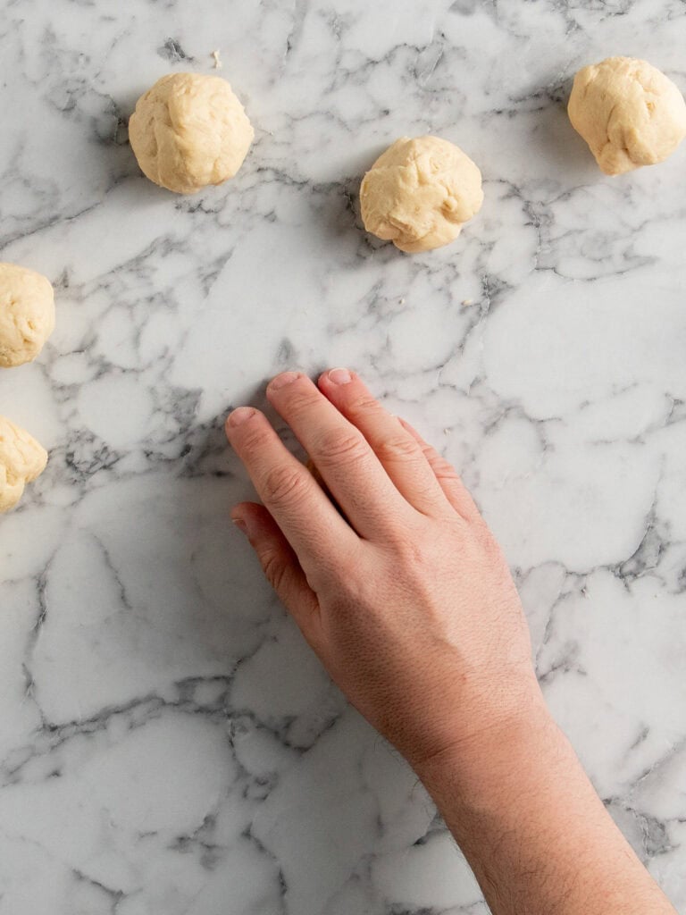 Cupping a hand over the dough portions to round them out