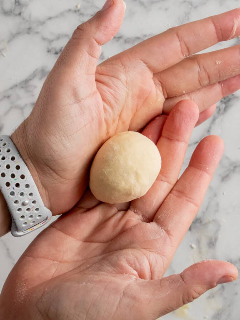 Using hands to pinch and round out the dough portions