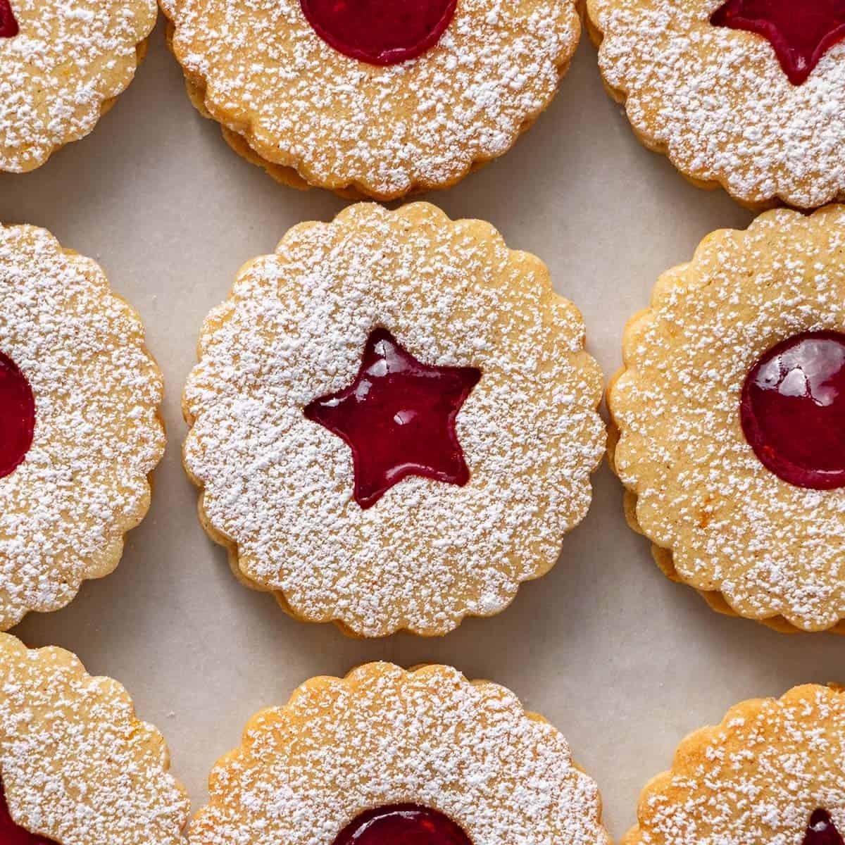 Square image top down shot of raspberry filled shortbread cookies with window shapes in the middle.