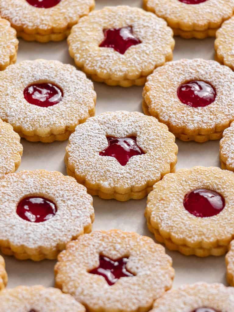 Raspberry filled shortbread cookies with window shapes in the middle and powdered sugar dusted on top