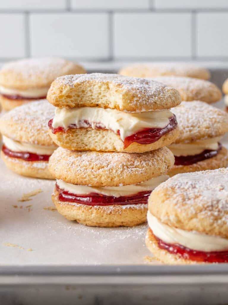 A stack of sponge cakes with cream and jam in the middle
