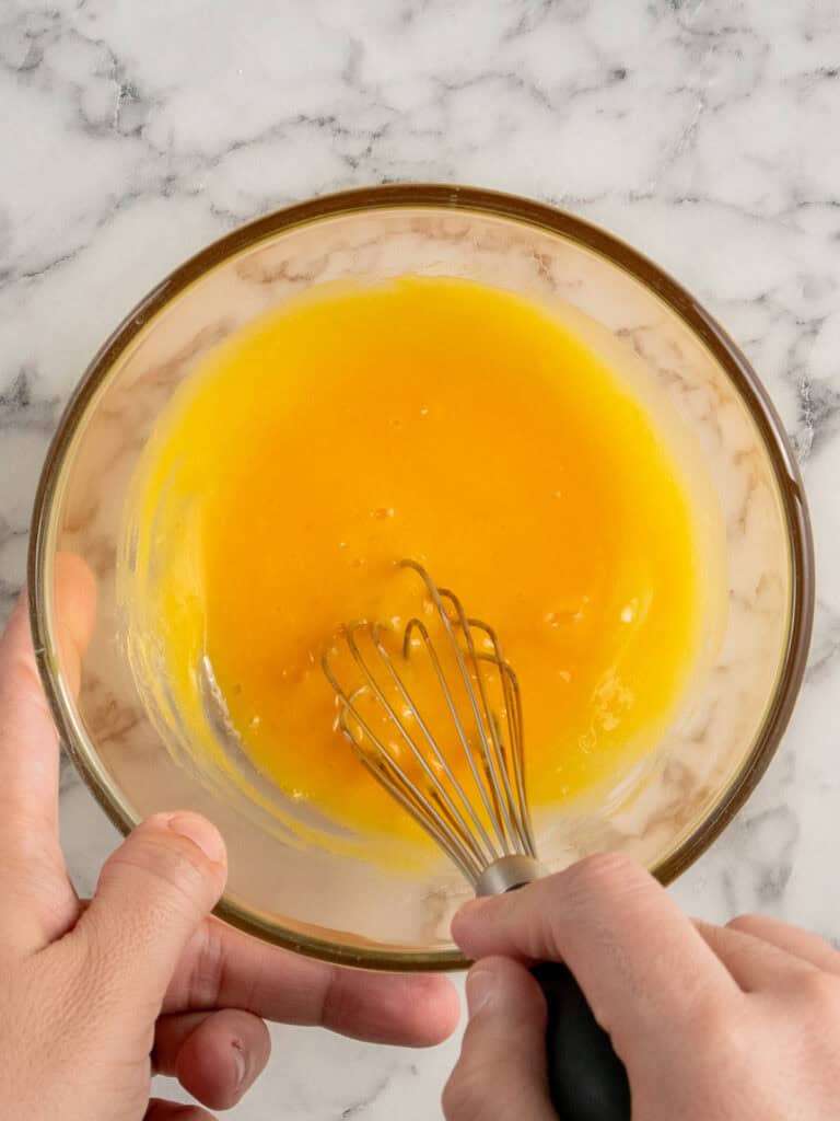 Whisking the egg yolks and melted butter to combine them