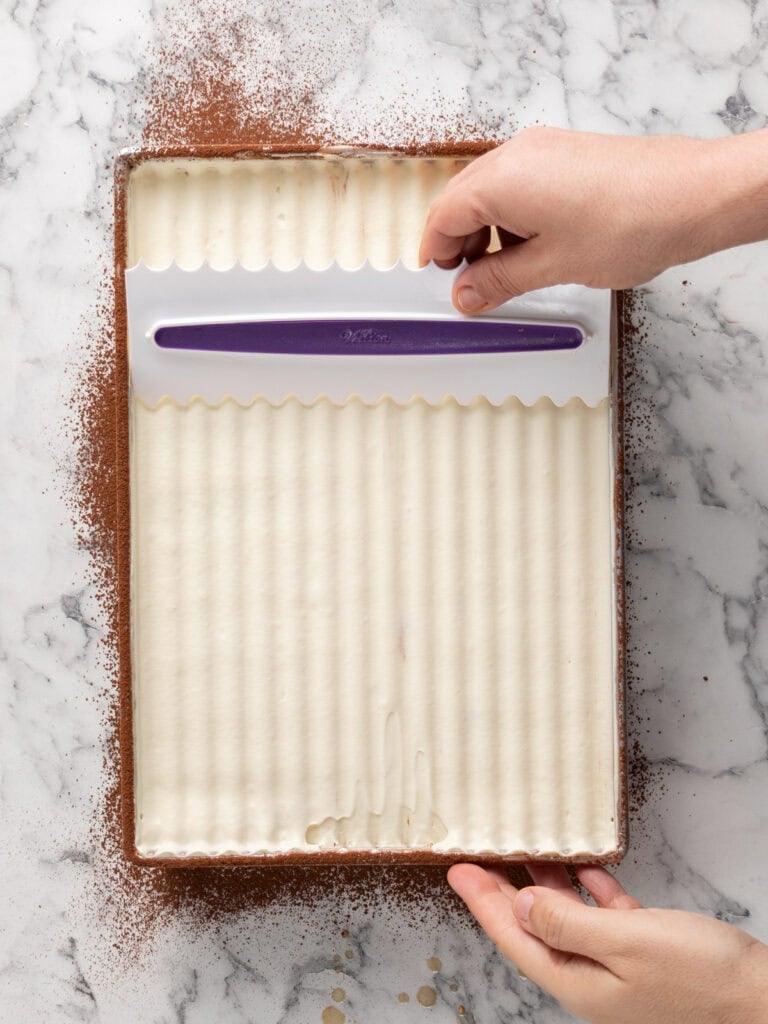 Use a cake scraper that is ridged to spread evenly and create a pattern