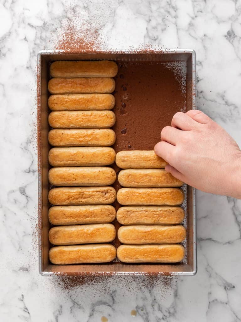 Add the soaked biscuits on top of the cocoa powder
