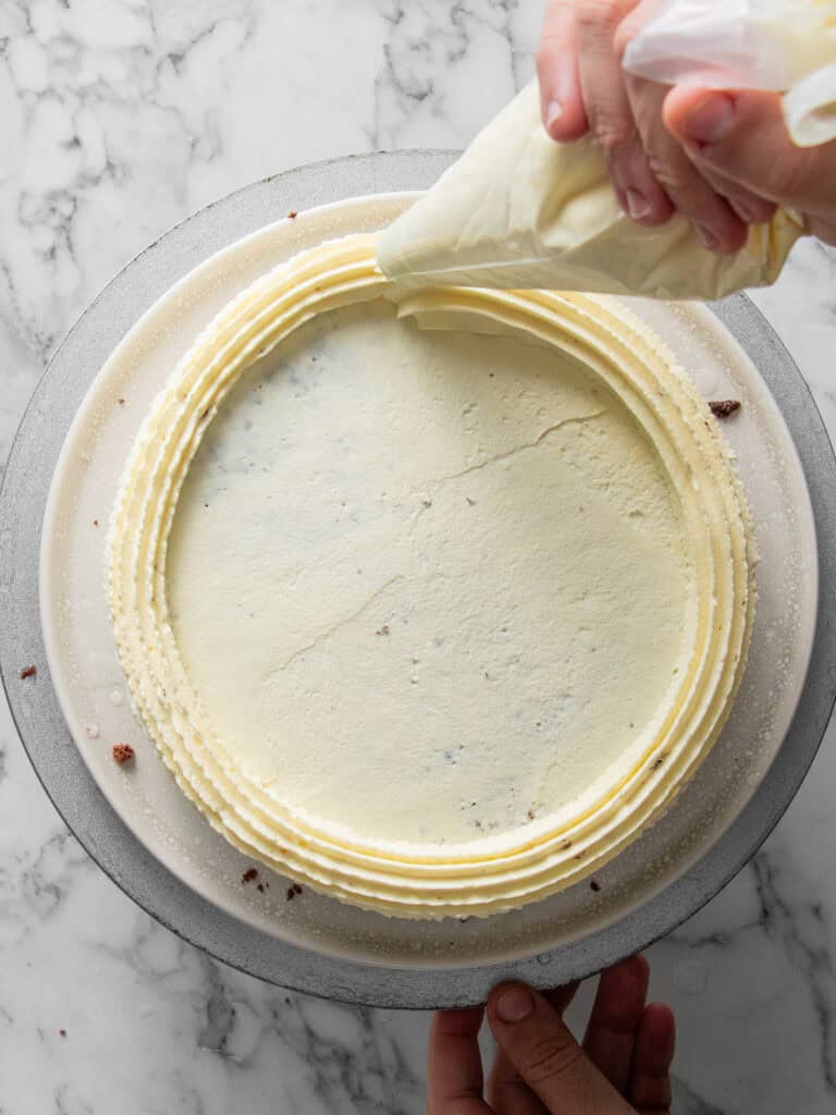 Creating a perimeter of Chantilly around the top of the cake