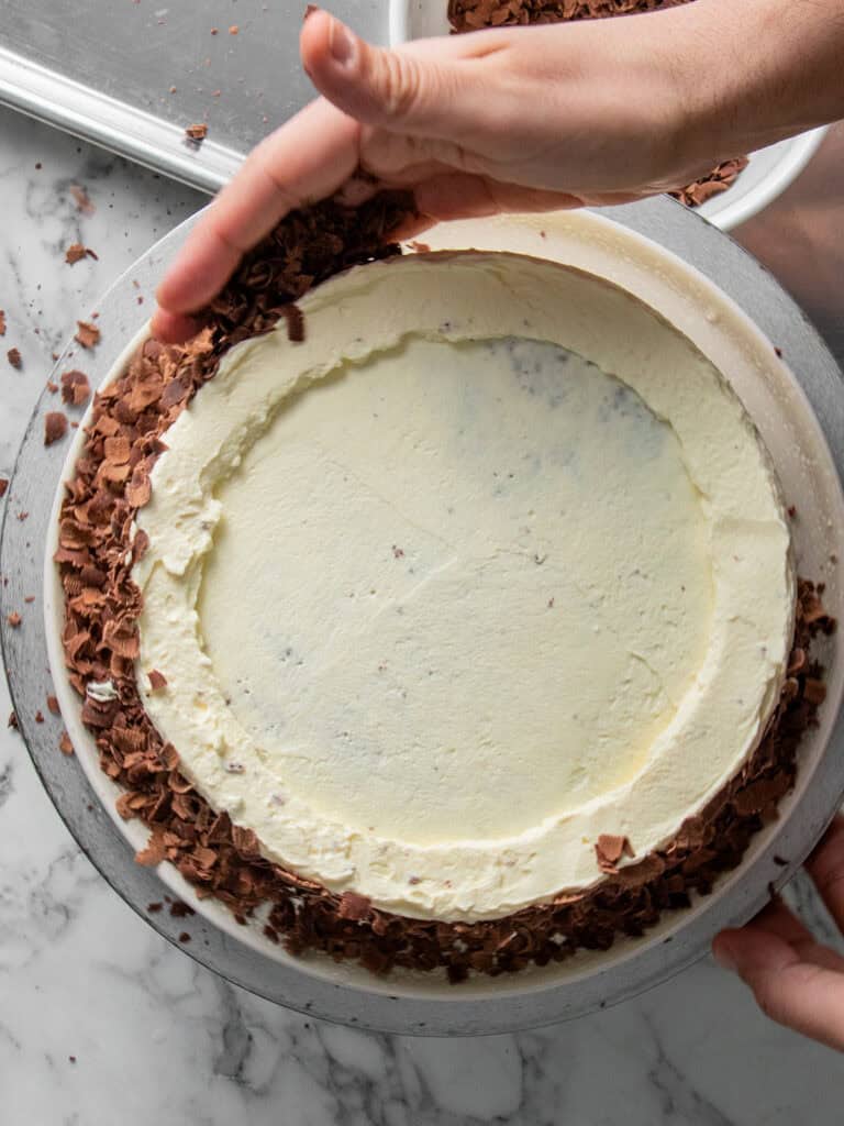 Adding chocolate curls to the outside of the cake