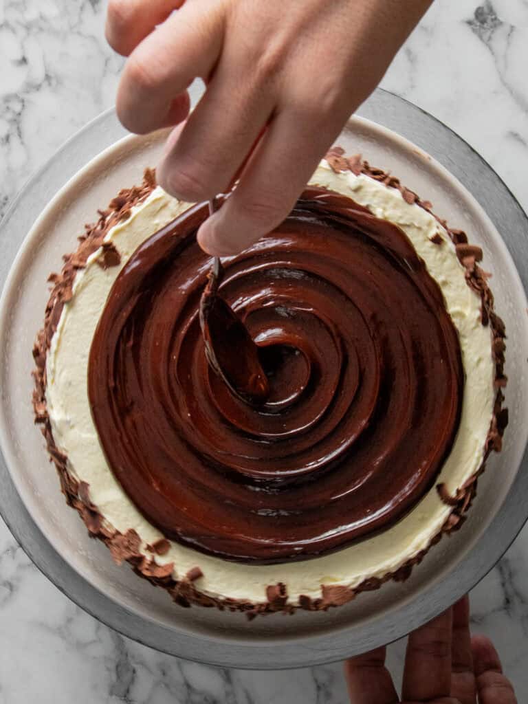 Adding chocolate sauce to the top of the cake