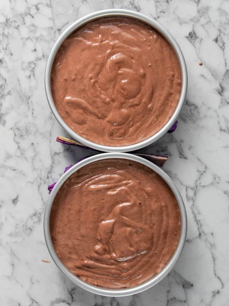 Adding the batter to the cake tins before baking the cakes