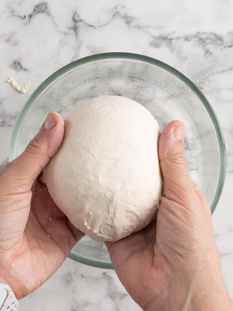 Pinching the dough ball at the bottom to form it into a ball