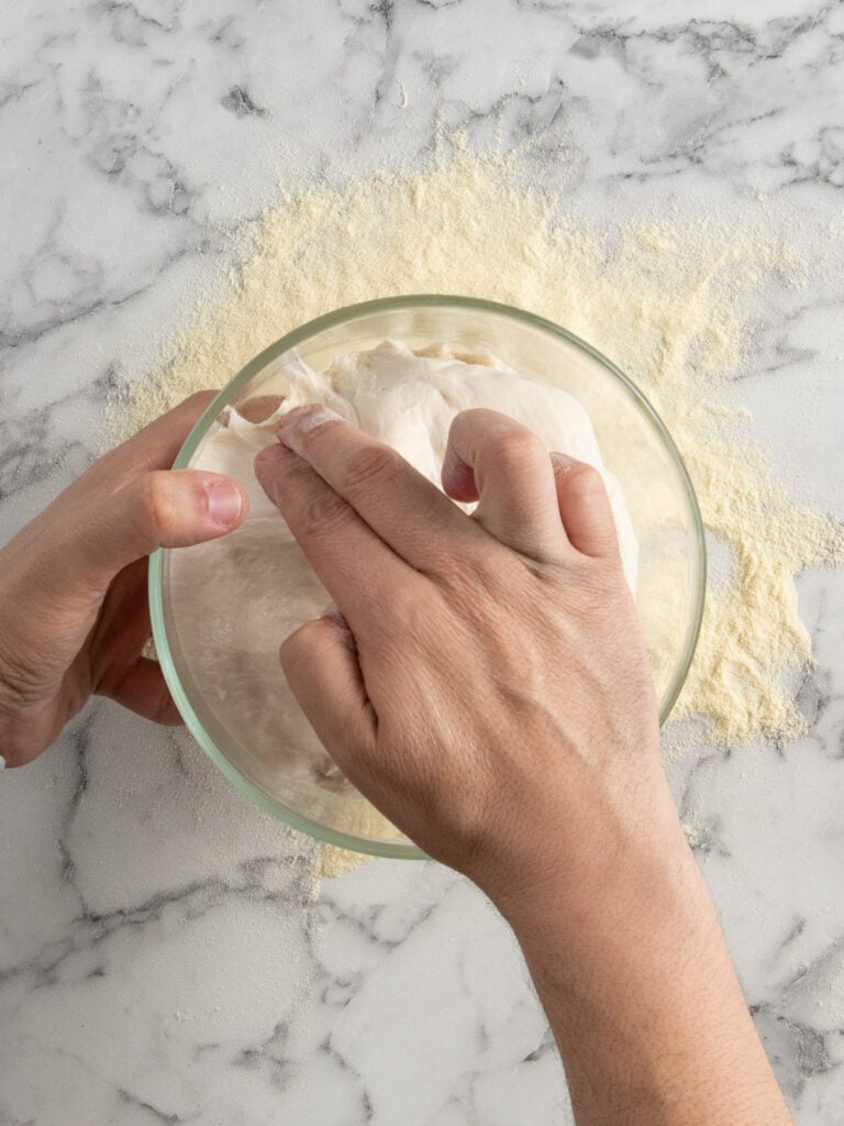 Pulling some of the dough away from the container to help it release better