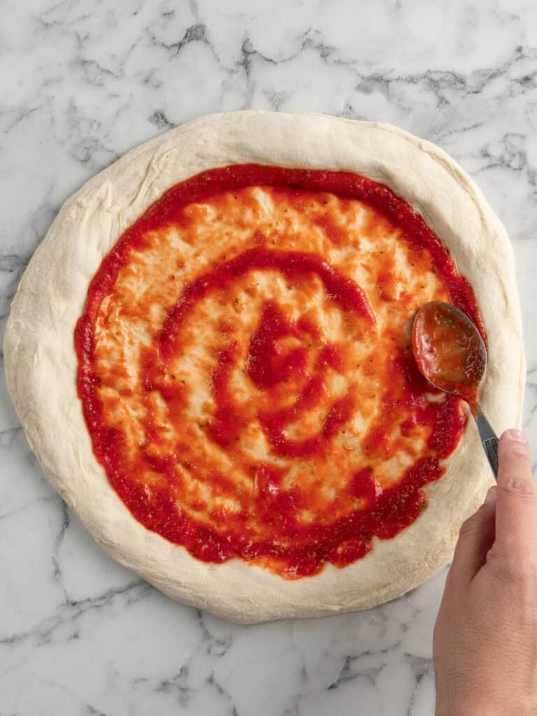 Spreading the sauce on top of the pizza
