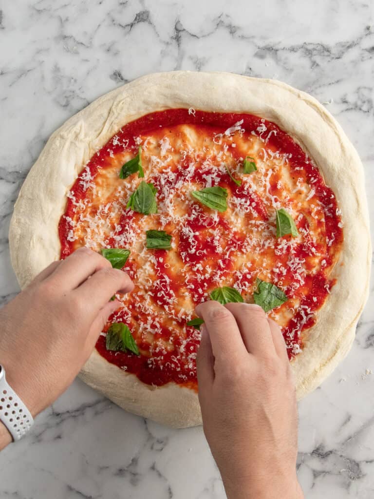 Adding torn up basil on top of the pizza