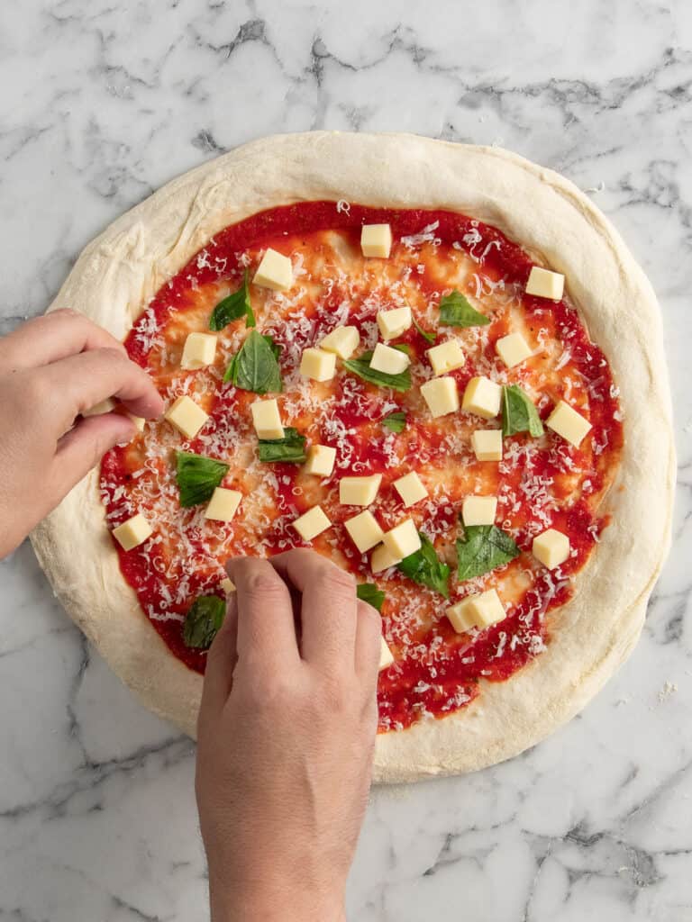 Adding cubes of mozzarella on top of the pizza