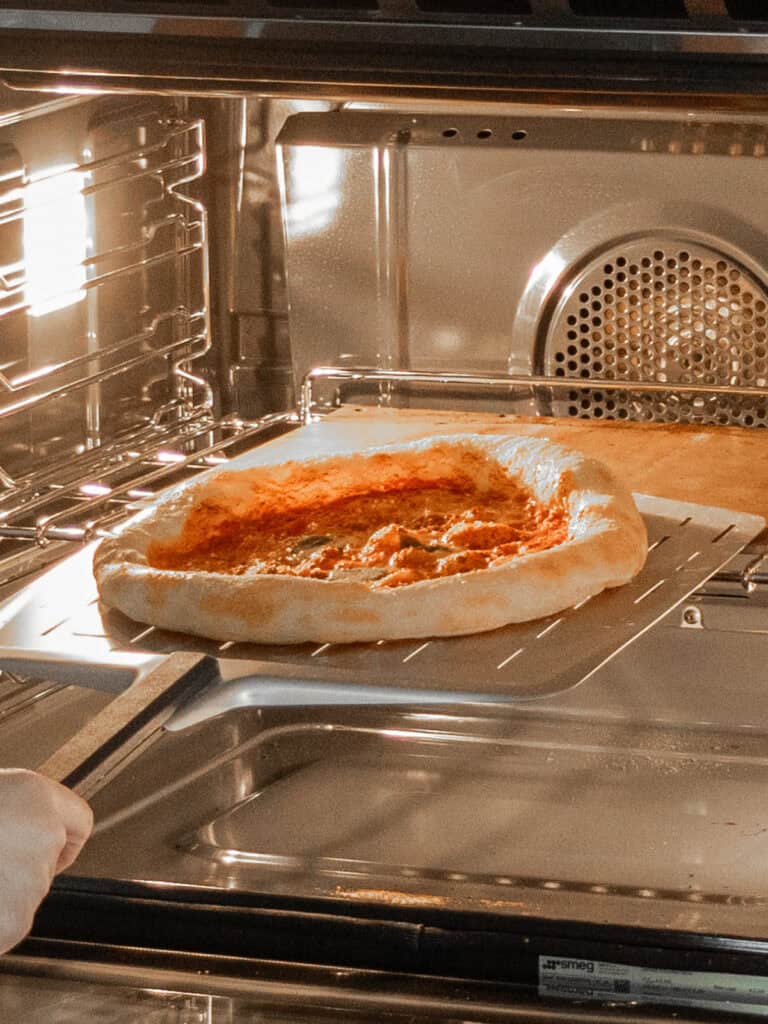 Taking the pizza out of the oven after it's baked