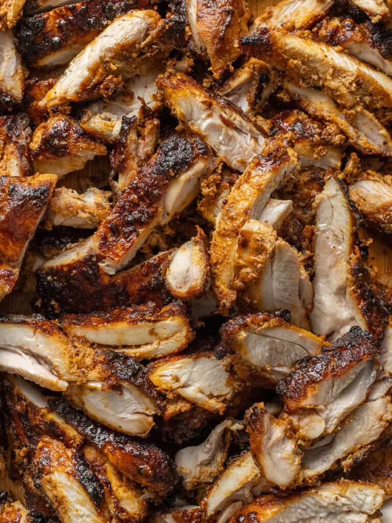 Close-up of juicy, grilled chicken pieces with a crispy, golden-brown, and slightly charred exterior, showcasing the texture and seasoning on the meat.